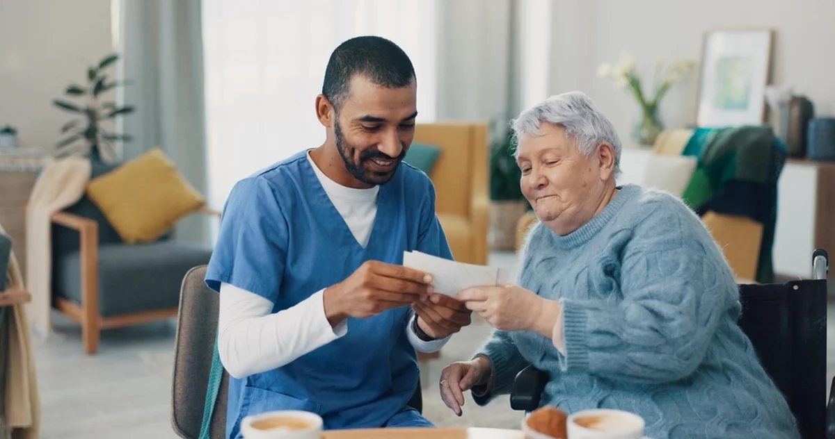 Nursing home, photo album and caregiver with old woman in retirement.