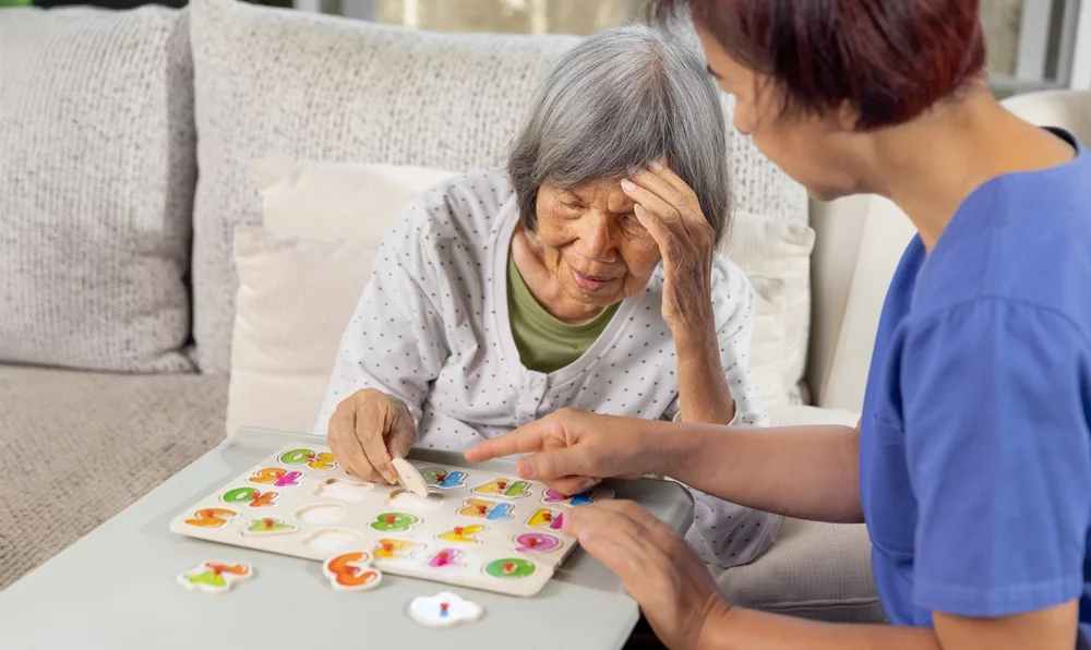 Nurse in nursing home helping a senior woman with number puzzle.